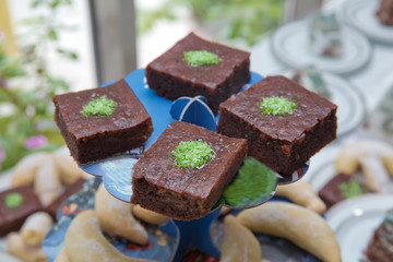 Integral Banana Cake . baked square pieces of chocolate pie with walnuts on a black board, top view . Delicious Chocolate Fudge Cake with Coconut Topping on a White Plate
