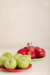 Red and green apples on a plate on a white background.