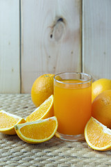 Orange and orange juice on wooden background as for clean drink.