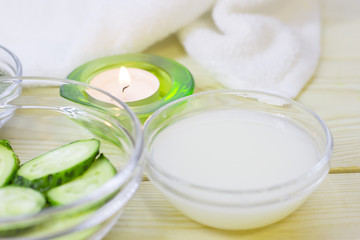 Obraz na płótnie Canvas Cucumber home spa and hair care concept. Sliced cucumber, bottles of oil, sea salt, bathroom towel. White board background