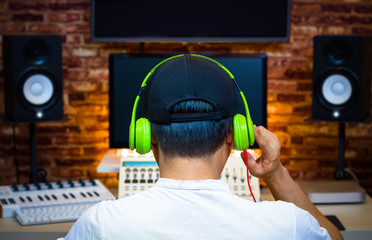 back of male asian music producer listening song in home recording studio
