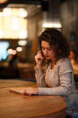 beutiful brunette business woman make notes in her notepad in cozy restraunt. dressed in gray knitted sweather