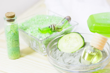 Cucumber home spa and hair care concept. Sliced cucumber, bottles of oil, sea salt, bathroom towel. White board background