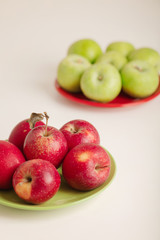 Red and green apples on a plate on a white background.