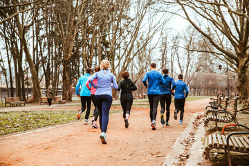 group of people running in city park in cold autumn day
