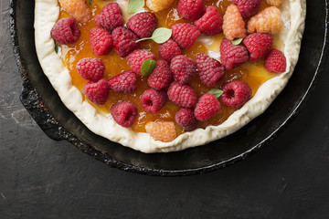 Homemade kitchen recipe. Cake with garden raspberries on yeast dough before baking in the oven in a frying pan. Top view.