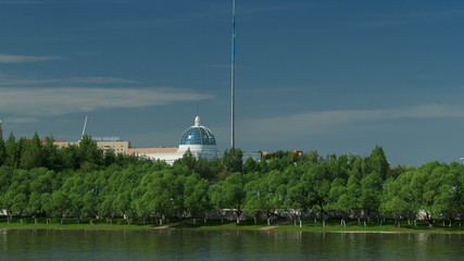 Fototapeta na wymiar river Ishim timelapse, buildings, premises, tratuar and trees in park. Sunny day. Astana, Kazakhstan