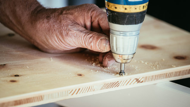Handwerker bohrt Loch in Holzplatte, H&auml;nde und Bohrmaschine, Heimwerker