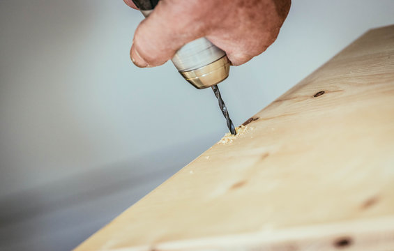Handwerker bohrt Loch in Holzplatte, H&auml;nde und Bohrmaschine, Heimwerker
