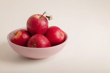 Red and green apples on a plate on a white background.
