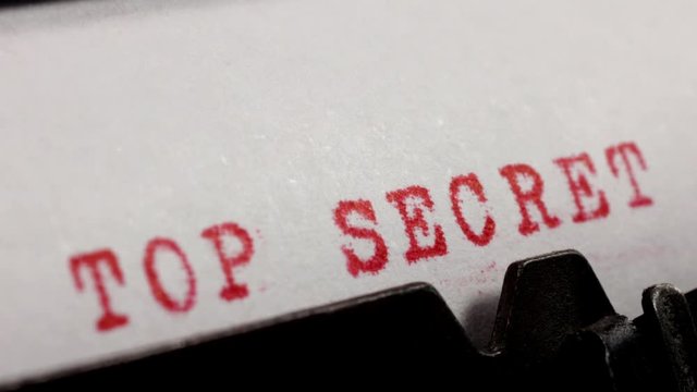 Typing TOP SECRET in red ink on an old mechanical typewriter.