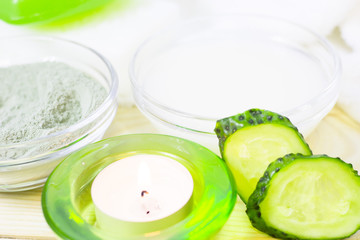 Cucumber home spa and hair care concept. Sliced cucumber, bottles of oil, sea salt, candle, bathroom towel. White board background