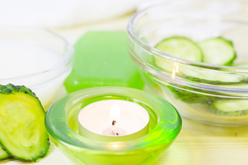 Cucumber home spa and hair care concept. Sliced cucumber, bottles of oil, sea salt, candle, bathroom towel. White board background