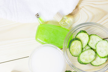 Cucumber home spa and hair care concept. Sliced cucumber, bottles of oil, bathroom towel. Straw light background
