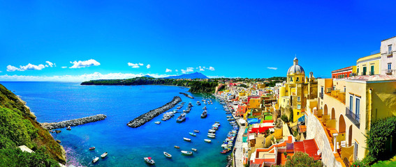 View of the Port of Corricella with lots of colorful houses on a sunny day in Procida Island, Italy.