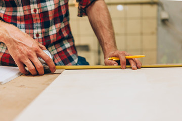 craftsman measuring with ruler and pencil on a wood board