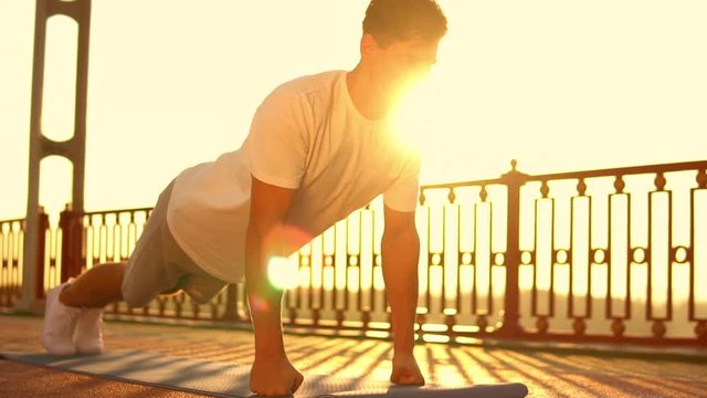male athlete works out on the bridge. caucasian guy has a street workout.