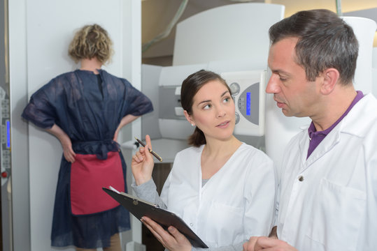 woman undergoing mammography scan assisted by doctors