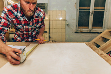 craftsman measuring with ruler and pencil on a wood board
