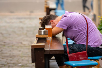 Sleeping man at a table next to the beer cup.