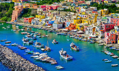 View of the Port of Corricella with lots of colorful houses on a sunny day in Procida Island, Italy.