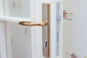 Close-up elements of the interior of the apartment. Detail of a white interior door with a door handle and latch . White door Golden handle . Golden door knob on the white door close up