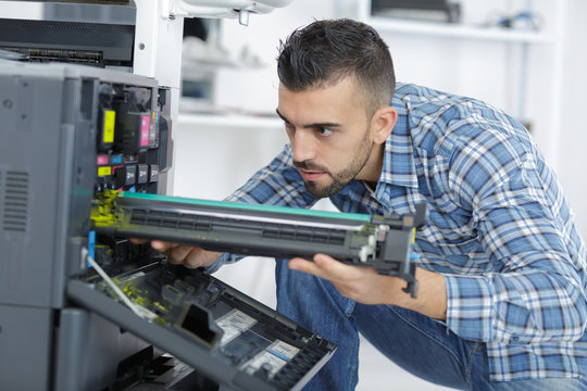 repairman fixing cartridge in photocopy machine at office