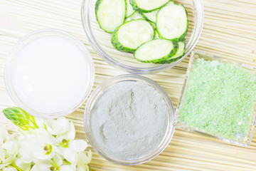 Cucumber home spa and hair care concept. Sliced cucumber, bottles of oil, sea salt, bathroom towel. Straw light background