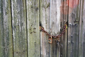 Vieja puerta de madera con cadena y candado oxidado.