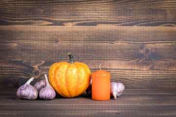 Halloween pumpkins, candle and garlic on a wooden background with copyspace