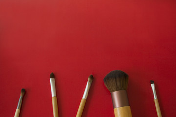  makeup brushes are placed on a red background.