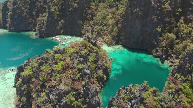 Aerial drone shot backwards over turquoise lagoons, limestone cliffs and Paraw boats, on a sunny day in Coron island, Philippines, Asia