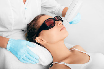 Woman getting laser hair removal in her face , laser procedure at clinic. Beautiful healthy female face