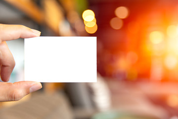 Obraz premium hand holding blank white business card with blur cafe background