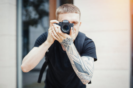 Close up of attractive man photographer making photos of modern building.