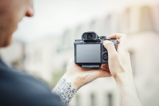Close up of man hands holding camera and making photos of modern building.