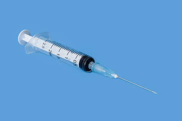 Fototapeta premium Transparent disposable syringe with needle on blue background.