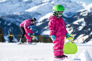 Fototapeta na wymiar Mother and little child skiing in Alps mountains. Active mom and toddler kid with safety helmet, goggles and poles. Ski lesson for young children. Winter sport for family. Little skier, swiss Alps