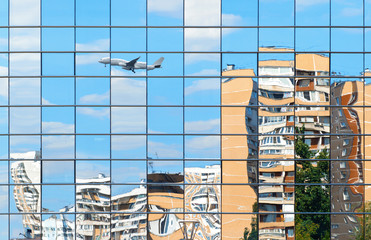 Residential buildings and plane are reflected in the mirror windows