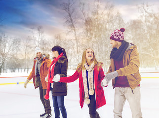 people, friendship and leisure concept - happy friends on skating rink outdoors