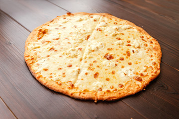 Homemade simple pizza with cheese on wooden background