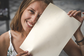 Junge lächelnde Frau hält leeres Papier 