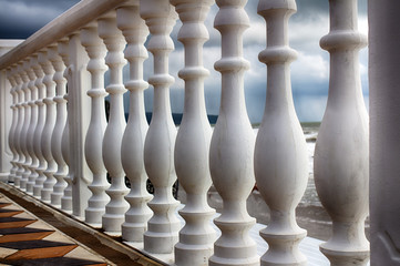 A row of white concrete balusters on the waterfront close-up.