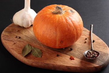 Small pumpkin and spices on a wooden cutting board