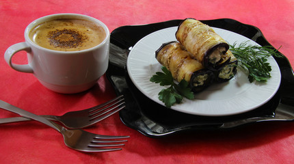 Tzatziki rolls grilled eggplant slices with cheese and tomato sauce closeup. Beautiful dinner with a cup of coffee on a red background.
