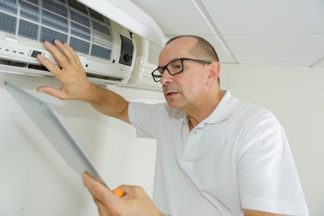 man using a tablet to adjust air conditioning system