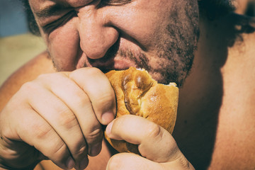 Fat man on the beach eating a pie