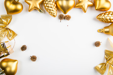 A top view of golden christmas ornaments positioned as a frame on white background