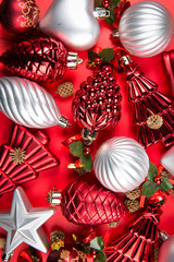 A top view of  mixed silver, red and green christmas ornaments on red background