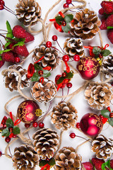 A top view of  mixed christmas ornaments: glazed pine cones, red  balls and berries on white background
